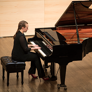 Young woman playing a grand piano at the Loyola School of Music and Theatre Arts.